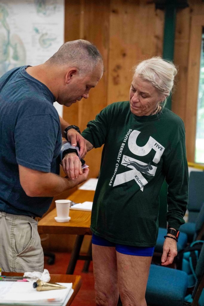Man applies medical tape to woman's arm